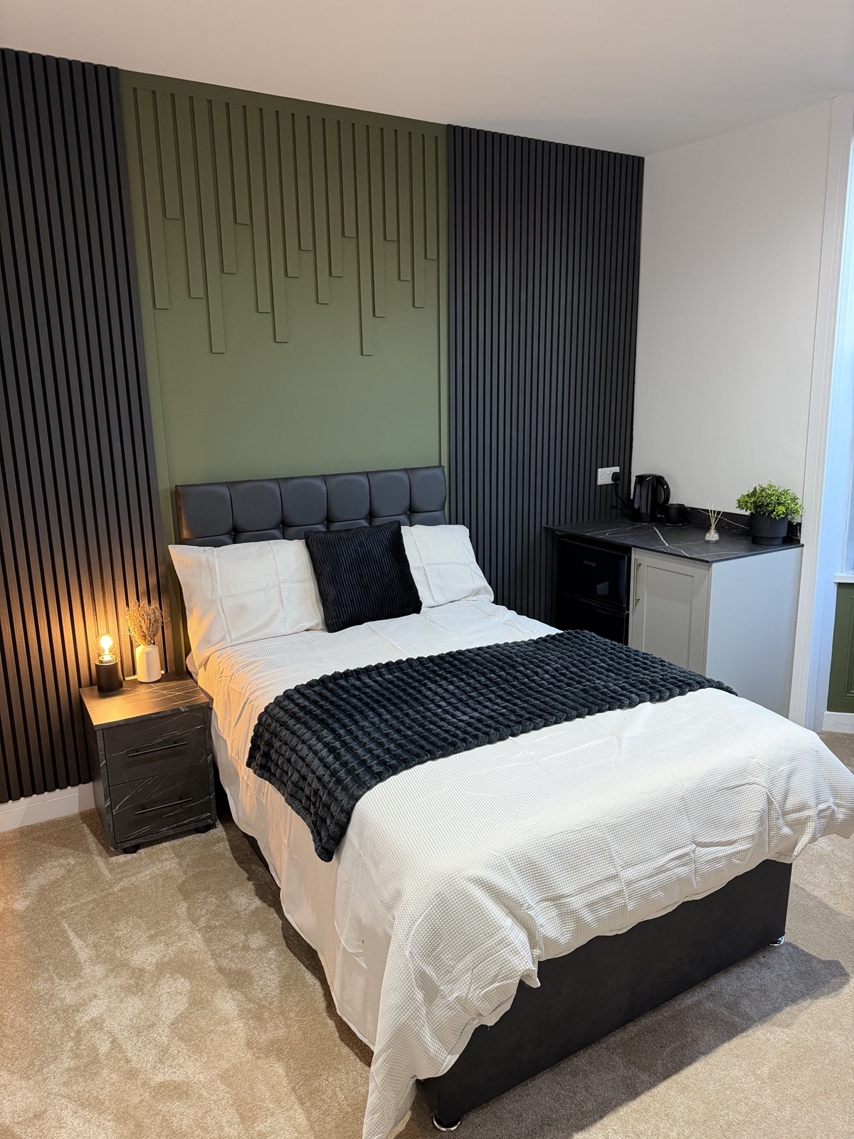 A double bedroom with green and black slatted feature panelling