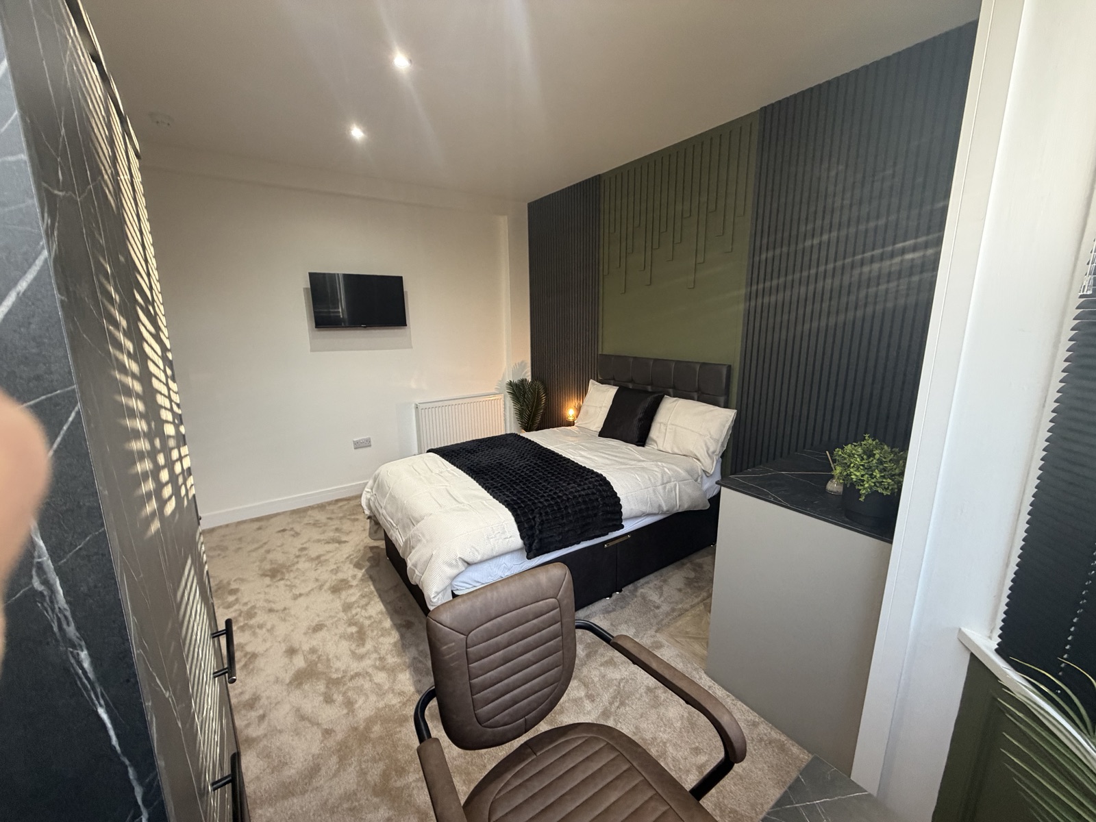A managed room with green and black slatted wall panelling and a work area